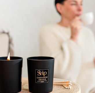 a woman sitting on a table with a cup of coffee and a candle is burning