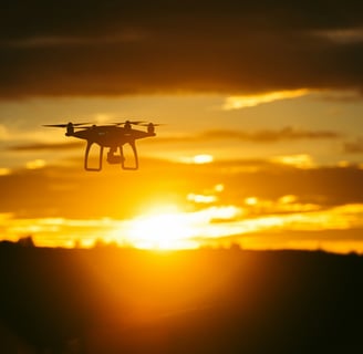 a small drone flying over a sunset