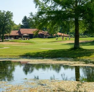 a golf course with a pond and a golf course golf club de la bresse