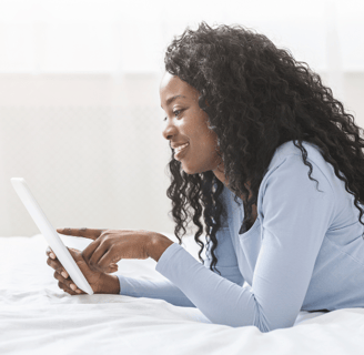 Black woman happily checking her Joyous ink newsletter emails