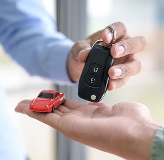 a person holding a car keychain and a small toy car