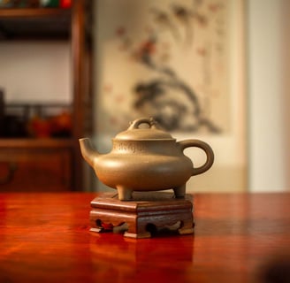 A clay-colored Yixing teapot is placed on a wooden stand
