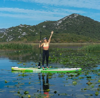 a woman standing on a paddle board on lake