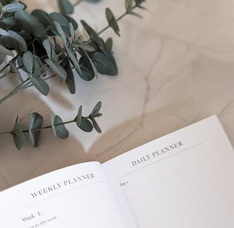 a plant on a table with open weekly planner
