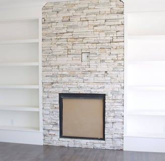 a white fireplace with stone facing and shelves