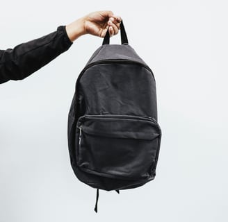 a person holding a black backpack in the air