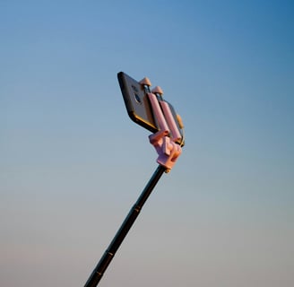 Phone on a selfie stick with blue sky background