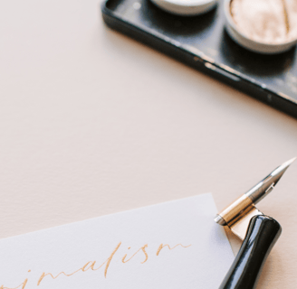 Stylo élégant placé à côté d'une palette de maquillage et d'un carnet.