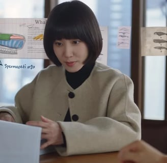 É a protagonista do Dorama (K-drama) Advogada Extraordinária segurando um papel na mão e pensando