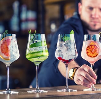 Barman in pub or restaurant preparing a gin tonic cocktail drinks in wine glasses