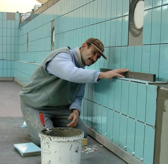 the image displays a guy installing tiles with the help of tile tools