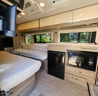 Sleeping area and kitchen of barely used 2023 Entegra Coach Ethos 20T Class B RV for sale.