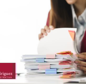 a woman in a red jacket is holding a folder and a laptop
