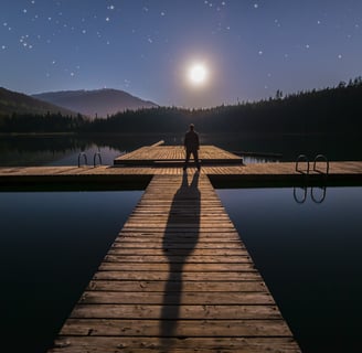 a person standing on a dock with a full moon