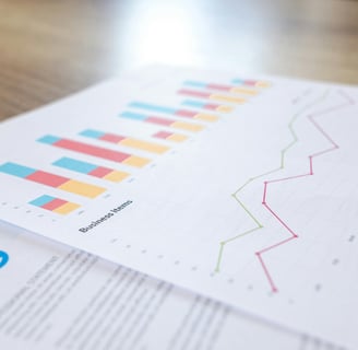 Two overlapping sheets of paper on a tabletop, the top one covered in graphs, a bar graph and a line graph.