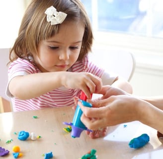 seorang anak kecil perempuan yang sedang bermain untuk melatih sensoriknya