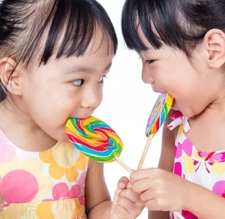 dua anak kecil yang sedang memakan permen