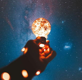 A lit bulb held up under a starry sky, symbol of the observing self