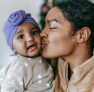 An image of a mother kissing her baby in a secure attachment