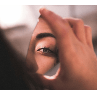fragment of a woman's face reflected in a shard of broken mirror