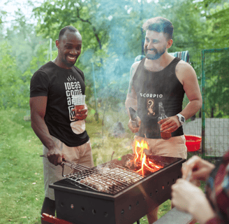 a man and a woman are standing around a grill