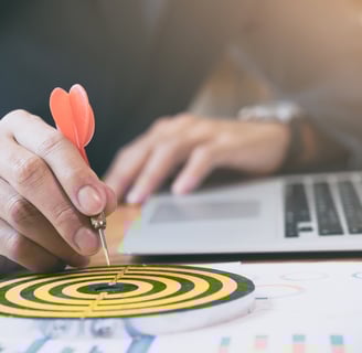 a person holding a dart and dart in front of a laptop