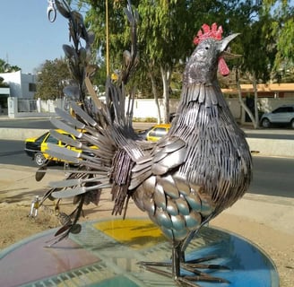 Sculpture métallique d’un coq grandeur nature, réalisée à partir de couverts recyclés