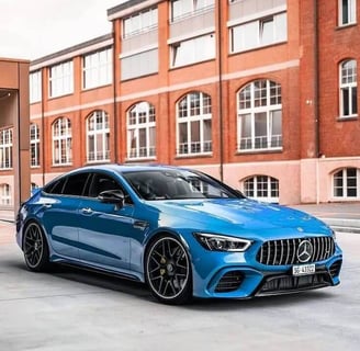 Blue luxury sedan parked in front of a modern brick building, showcasing professional auto detailing
