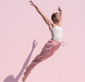 Dancer jumping against a pink backdrop.