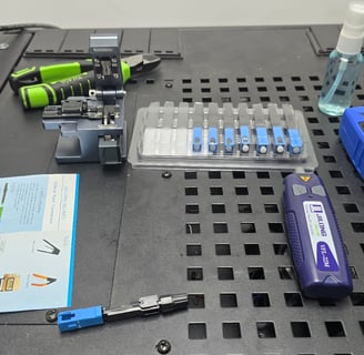 Mesa de trabajo con herramientas para instalación de conectores de fibra óptica SC/APC y equipos de medición óptica.
