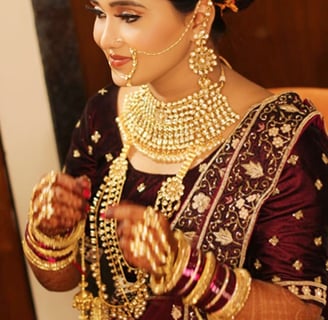 A woman is adorned in traditional bridal attire, featuring intricate jewelry such as a heavy necklac