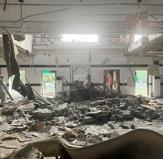 Interior view of a severely damaged building with debris scattered across the floor, b