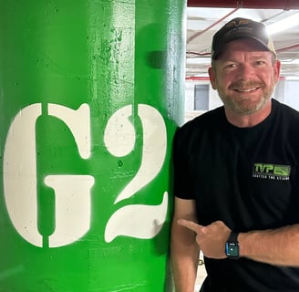 Andrew pointing at a sign in a parking garage that says G2