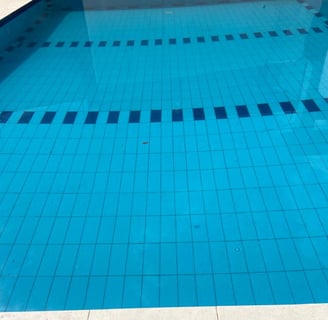 a pool with a blue tiled pool and a white tiled floor