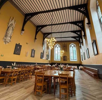 Pugin Hall with refectory tables separated by wide aisles and with parquet floor