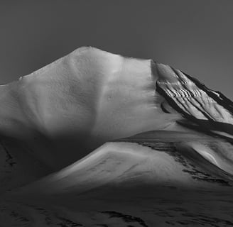 a snow covered mountain in black and white