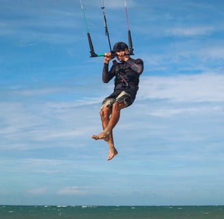 homem pulando de kitesurf na praia.