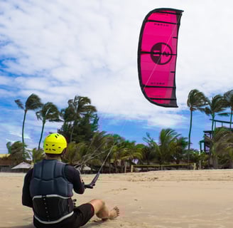 homem controlando o kitesurf sentado na praia