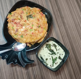 alt="Crispy and fluffy Uttapam served with coconut sauce on a wooden table"