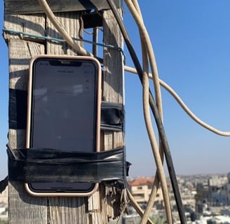 Palestinians hang a phone in a high place in an attempt to catch an internet signal.
