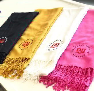Custom embroidered graduation stoles in black, gold, white, and pink with Colorado Springs Schools l