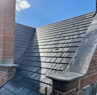 high quality slate roof with copping stones on a parapet wall and chimney 