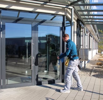 Ein Fensterputzer reinigt eine große Glasfront an einem Gebäude. 