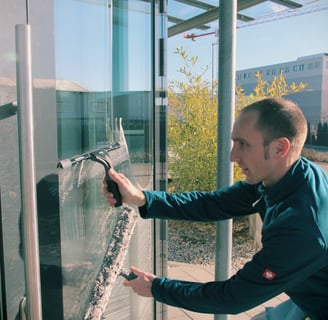 Ein Fensterputzer reinigt eine große Glasfäche. 