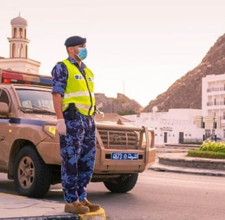 a man in a yellow vest and blue pants standing in front of a car