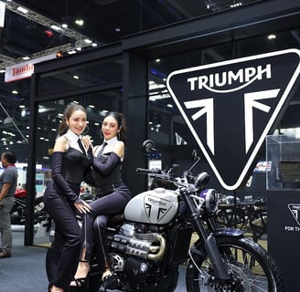 a woman standing next to a motorcycle with a woman sitting on it