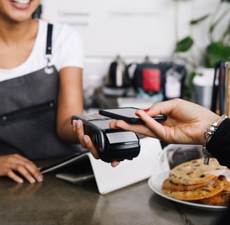 A customer pays using her phone connecting to a wireless point of sale terminal.