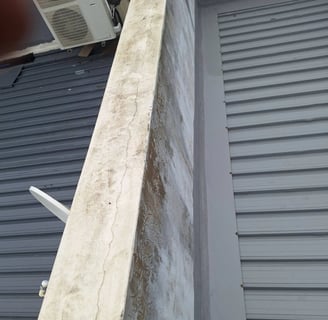 Cracks at parapet wall where waterproofing has failed on a flat roof slab