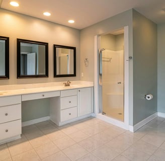 Image of basic bathroom with double vanity, framed mirrors, and enclosed shower