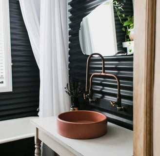 Modern bathroom with round basin and copper tap against dark panel wall